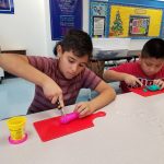Two boys cutting up pieces of Play-Doh