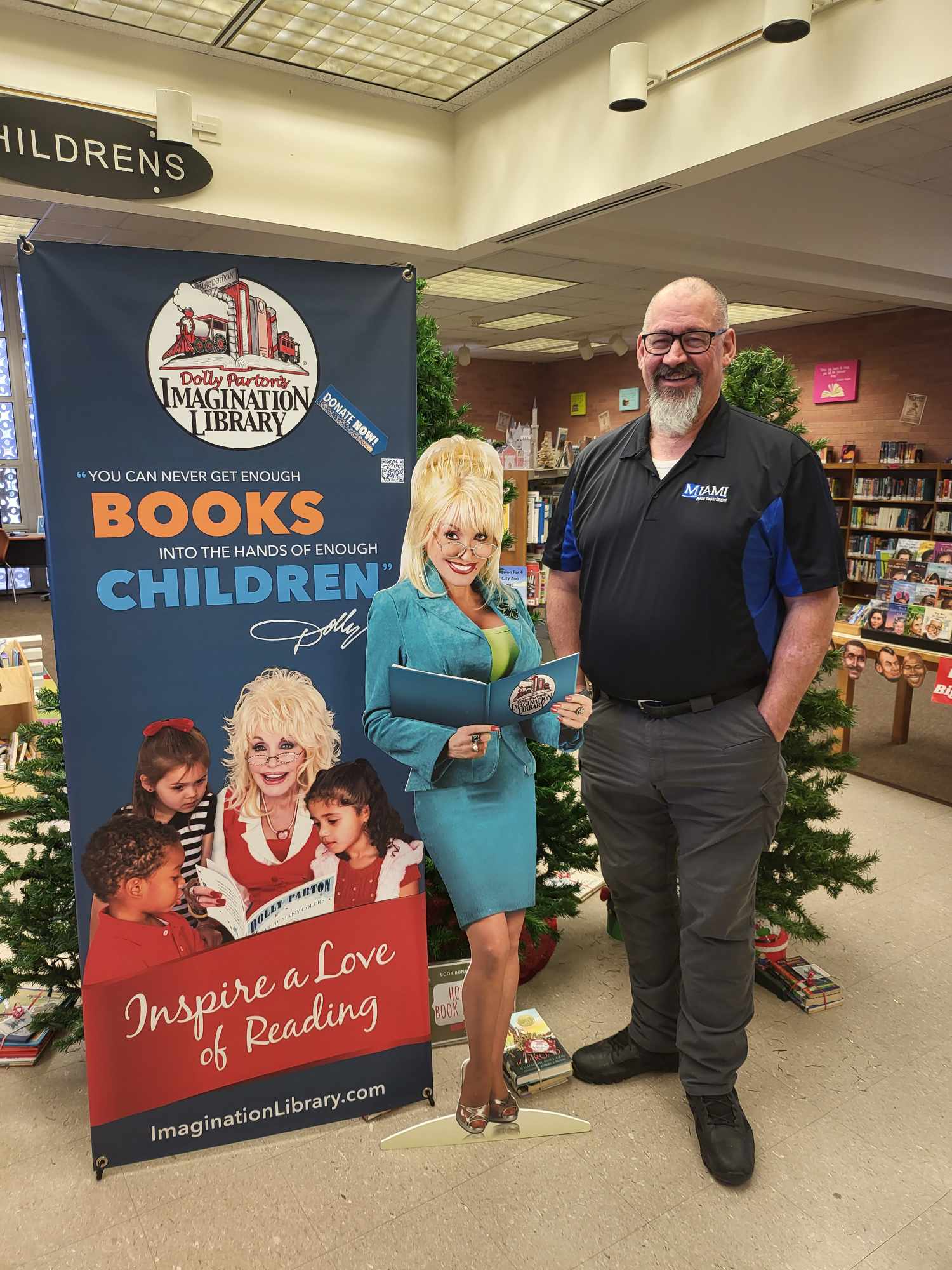 Chief Anderson also known as "Hightower" standing in Miami Public Library next to a life-size Dolly Parton cutout.
